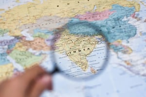 A magnifying glass focusing on India, making the country’s details stand out vividly. The surrounding regions on the map are intentionally blurred to emphasize the central focus.