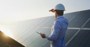 An-young-engineer-is-checking-with-tablet-an-operation-of-sun-and-cleanliness-on-field-of-photovoltaic-solar-panels-on-a-sunset